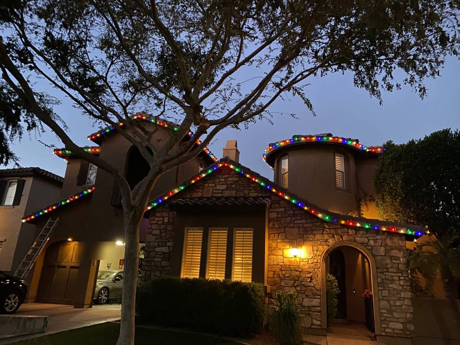 Stone-front home with multicolor C9 bulbs along the rooflines