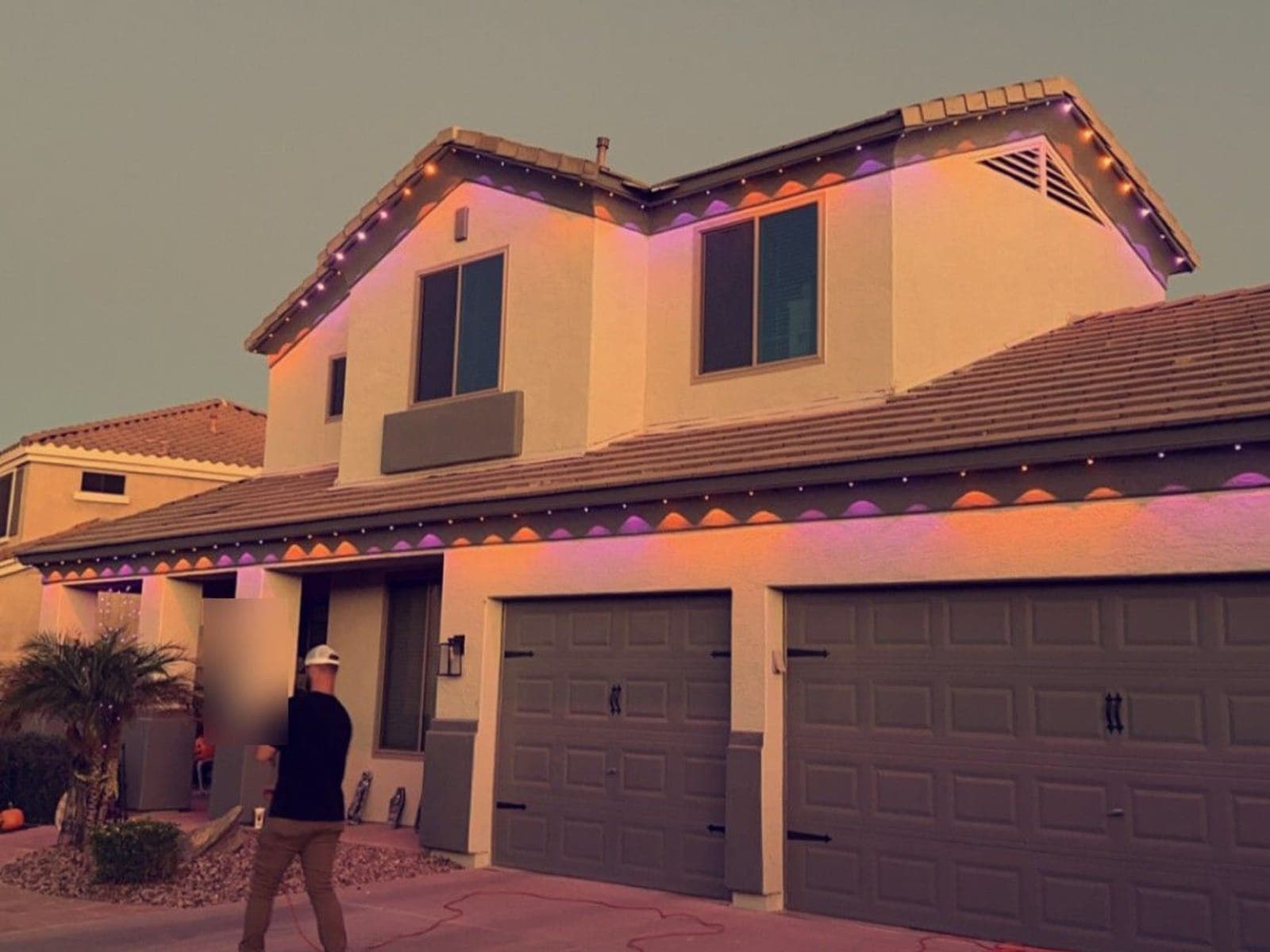 Installer checking orange and purple roofline lights at dusk